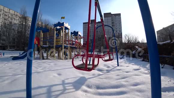 在阳光明媚的冬日空孩子在城市公园的操场上荡秋千从底部看背光广角视频的预览图