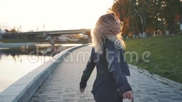 女人走在城市的河岸上在夕阳前视频的预览图