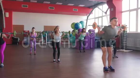 在训练中举重一组男女青年在健美操课上做练习有杠铃的女孩视频的预览图
