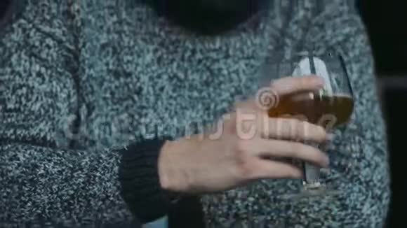年轻迷人的蓝眼大胡子男人穿着一件温暖的毛衣喝着啤酒对味道感到惊讶目光正朝着视频的预览图