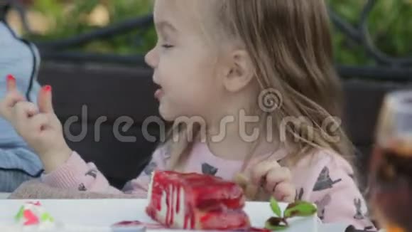 在儿童户外咖啡馆吃芝士蛋糕酱的小女孩视频的预览图