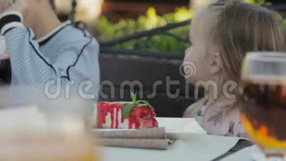 在儿童户外咖啡馆吃芝士蛋糕酱的小女孩视频的预览图
