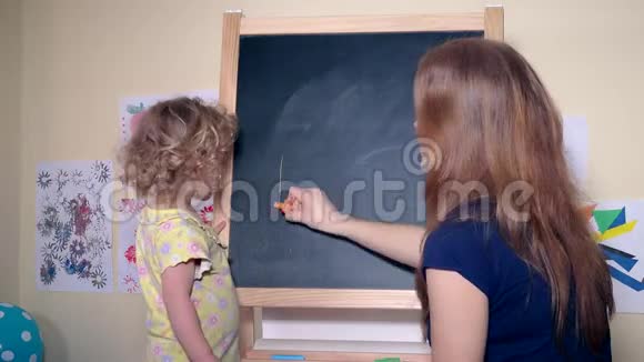 幸福的家庭女孩妈妈和女儿在黑板上写字爸爸视频的预览图