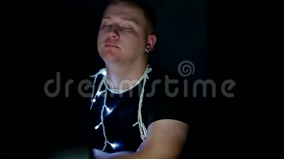 悲伤的年轻人戴着圣诞花环用电脑视频的预览图