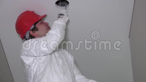 疲劳的男工戴着红色头盔在天花板上凿洞视频的预览图