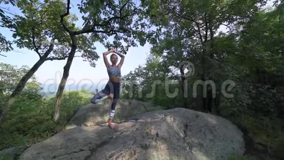 年轻女子正在一座山顶上美丽的异国情调的地方练习瑜伽瑜伽和冥想视频的预览图