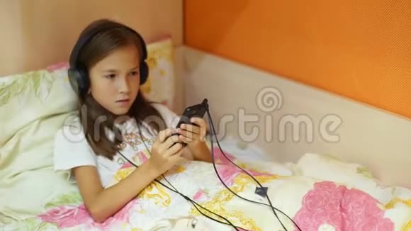 带着耳机在床上听音乐的小女孩视频的预览图