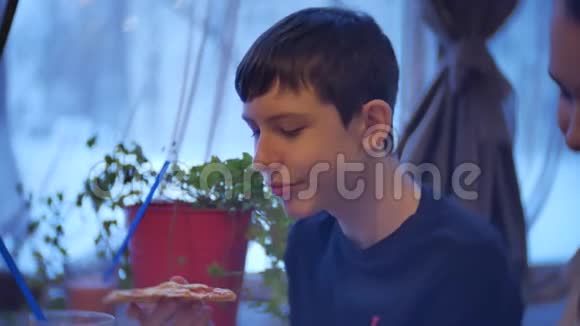 男孩十几岁的孩子吃披萨坐在咖啡馆里快餐慢动作视频室内视频的预览图