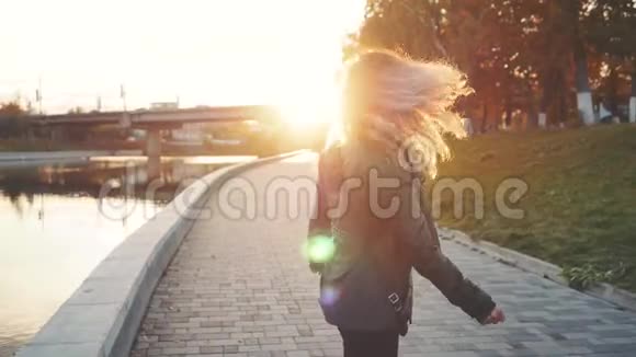 女人走在城市的河岸上在夕阳前视频的预览图