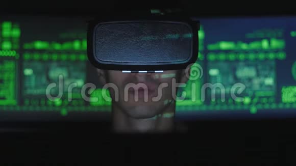 男性黑客程序员使用虚拟现实头盔编程而绿色代码字符反映在他的脸上它视频的预览图