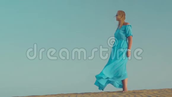 在海滩上穿蓝色裙子的女人视频的预览图
