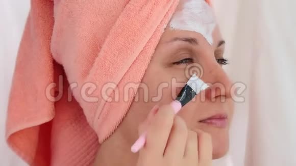 漂亮的年轻女人用刷子敷一个化妆面具视频的预览图