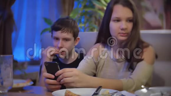 一群朋友坐在咖啡馆里拿着智能手机孩子们在室内的咖啡馆里吃披萨视频的预览图