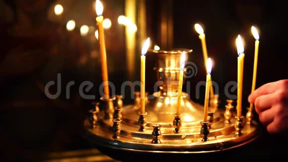 人们在东正教的烛台上纠正燃烧的蜡烛视频的预览图