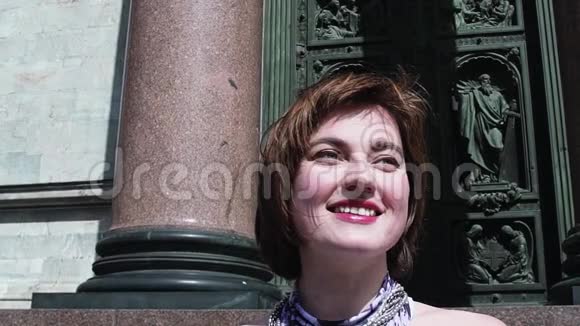 穿着夏装的开朗女人微笑着面对古老的正统教堂门视频的预览图