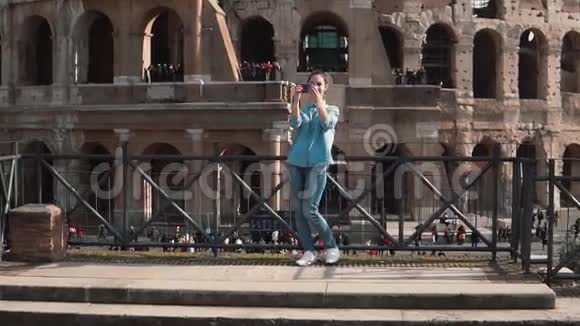 旅游女用智能手机在意大利罗马竞技场拍照女孩跑下台阶慢动作视频的预览图