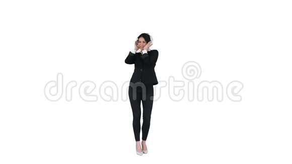 年轻的商务女性听着耳机里的音乐在白色背景下跳舞视频的预览图