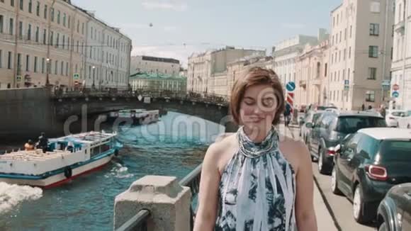 穿着斑点裙子的漂亮女孩沿着老市中心的河流唱歌视频的预览图