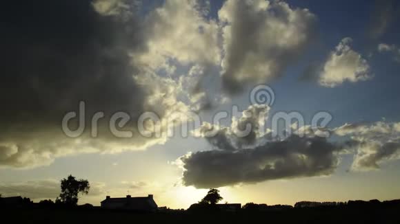 夕阳下的积云在一段时间内快速地掠过乡村法国欧洲的房屋农场树木的剪影M视频的预览图