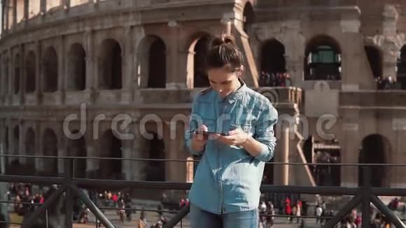旅游妇女看她的智能手机上的建筑物照片意大利罗马竞技场的背景慢动作视频的预览图