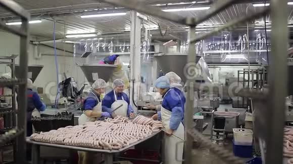 穿制服的工人做香肠肉类加工厂的员工把香肠铺在金属棒上视频的预览图