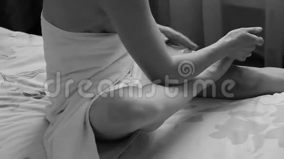 迷人的女孩穿着毛巾与整洁的身体应用化妆品脚霜做脚按摩家里的SPA视频的预览图