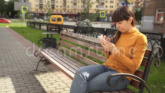 坐在路边长凳上打电话的年轻女子视频的预览图