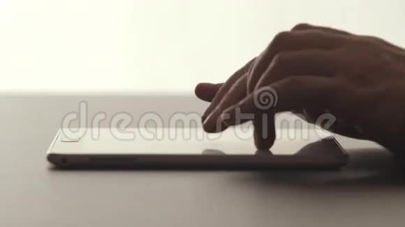 侧面视图人的手触摸桌子上的平板电脑视频的预览图