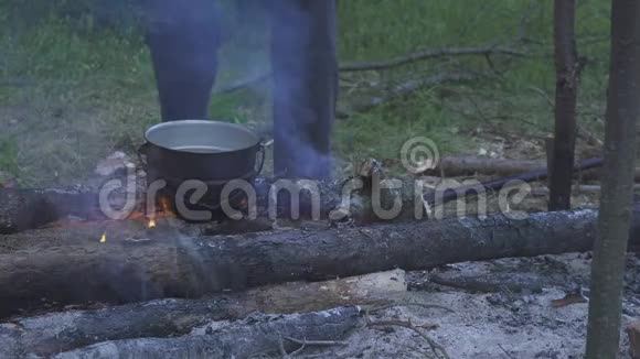 游客在森林中的傍晚在火堆中沸腾品尝晚餐视频的预览图