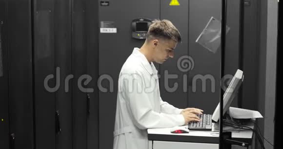 IT技术人员在大数据中心的一台电脑上工作里面装满了Rack服务器他运行诊断和维护系统视频的预览图