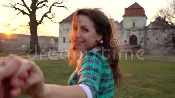 慢动作跟着我快乐的年轻女子在一座古老城堡背景下拉着男孩的手视频的预览图