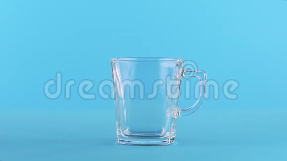 慢动作特写镜头牛奶冷饮调成玻璃杯手柄蓝色背景在工作室视频的预览图