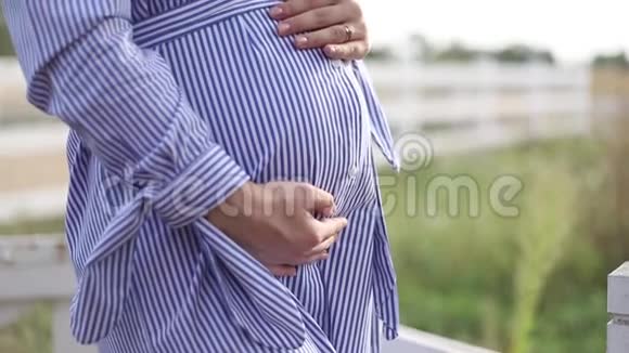 近距离观看大自然中怀孕的腹部女人抱着花束抚摸她的腹部视频的预览图