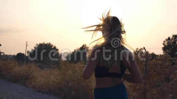 跟随运动女孩在乡间小路上慢跑戴墨镜的年轻女子在户外跑步听音乐视频的预览图