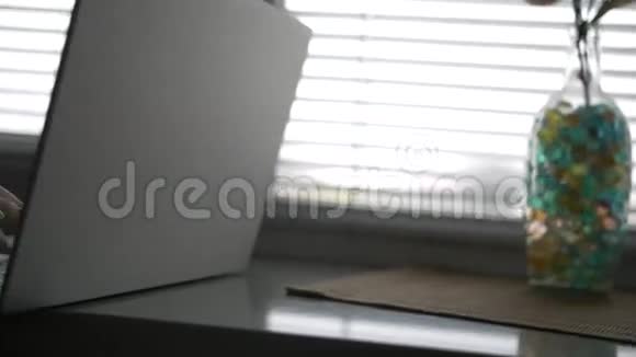 窗户边拿着笔记本电脑的女人的手视频的预览图