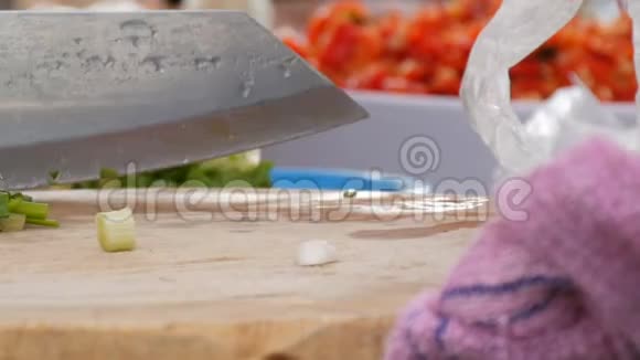 女人用一把大刀在厨房板上切绿色蔬菜和炊具旁边泰国视频的预览图