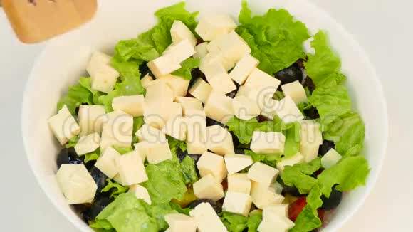 一个女人用橄榄油准备一份希腊蔬菜和奶酪沙拉视频的预览图