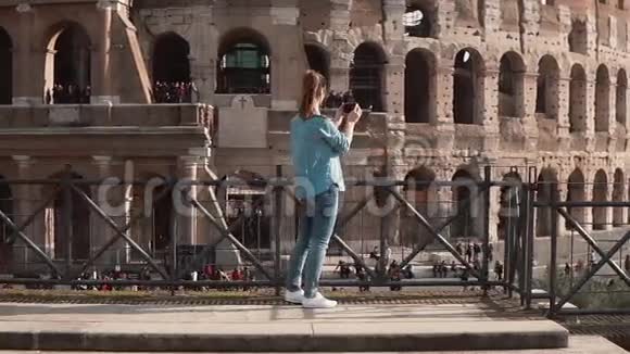 在意大利罗马布鲁内特旅游妇女站在镜头前用智能手机拍摄竞技场的照片慢动作视频的预览图