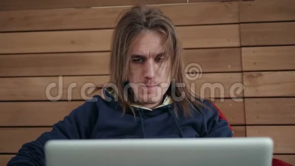 一位有创造力的男性自由职业者坐在笔记本电脑前的后视图年轻的商人在上网本工作期间视频的预览图