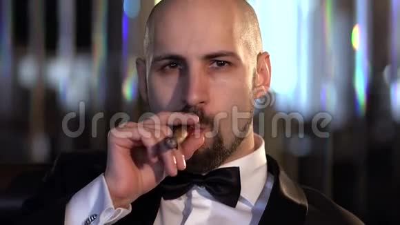 优雅的男人穿着西装抽着雪茄看着相机动作缓慢视频的预览图