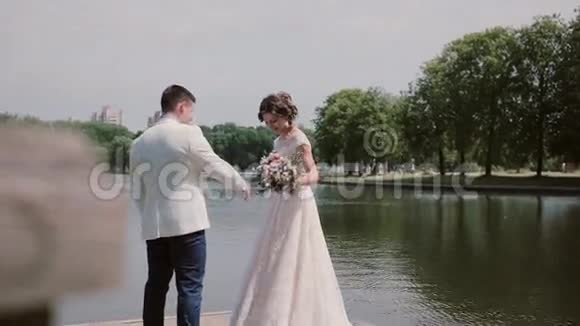 可爱的情侣在码头上美丽的新娘展示她的婚纱旋转着快乐的恋人笑着享受快乐的一天视频的预览图