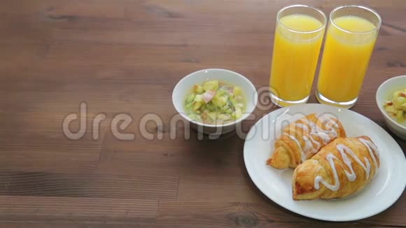 木桌上摆着两杯橙汁和两个盘子上面放着muesli和水果摄像机从左向右移动视频的预览图