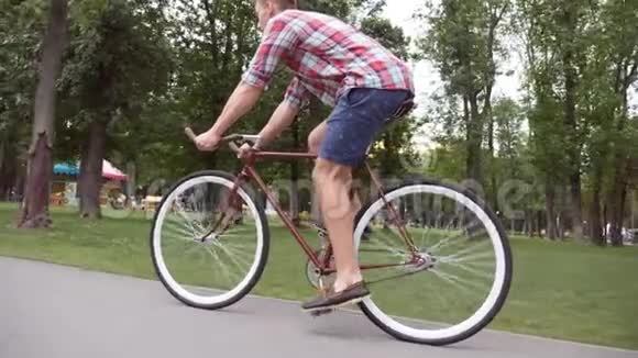 运动男在公园路骑自行车年轻的帅哥骑着一辆老式自行车在户外健康的积极生活方式侧面视频的预览图