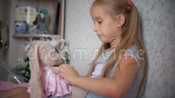一个漂亮的小女孩和一只玩具兔子在家里穿裙子家庭关系孩子拥抱可爱的玩具视频的预览图