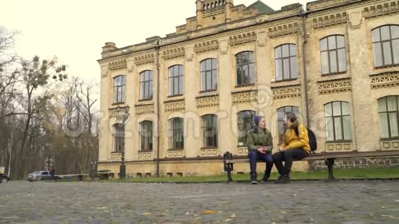 学生们坐在大学附近公园的长凳上互相交谈视频的预览图
