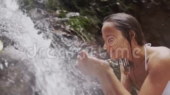 快乐的女孩在天然瀑布中的水流中洗脸慢动作1920x1080视频的预览图