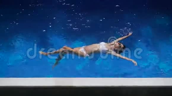 可爱的女人穿着白色比基尼在水里游泳年轻的女孩正在表现出安慰和快乐视频的预览图