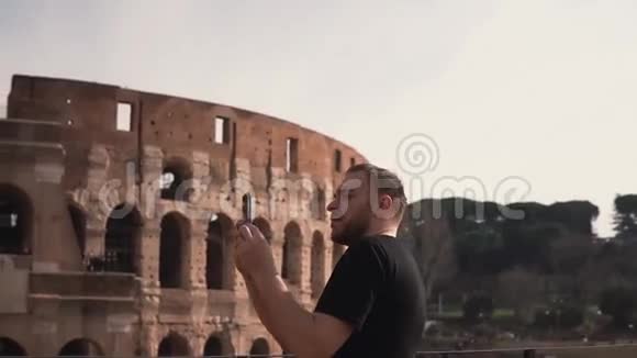 一位英俊的男子访问意大利罗马在竞技场附近拍照他喜欢旅行建筑慢动作视频的预览图