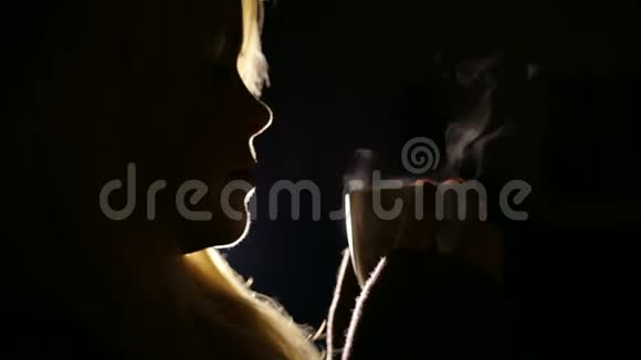 一个在黑暗中喝着一杯热茶的女孩的剪影视频的预览图