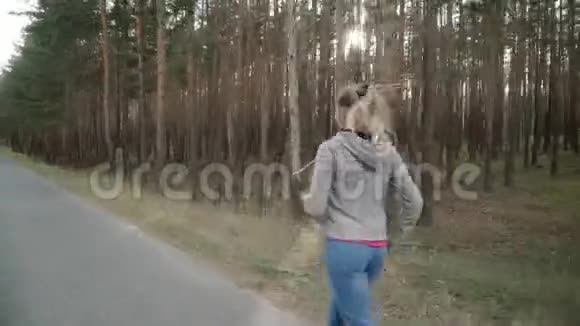 一个女孩沿着松林里的沥青路跑视频的预览图